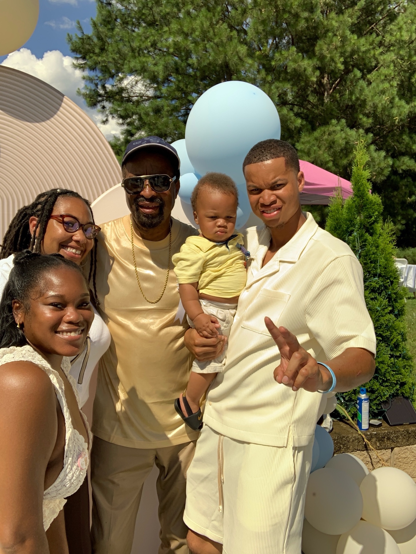 Family with a baby posing at an outdoor photo booth with pastel balloons
