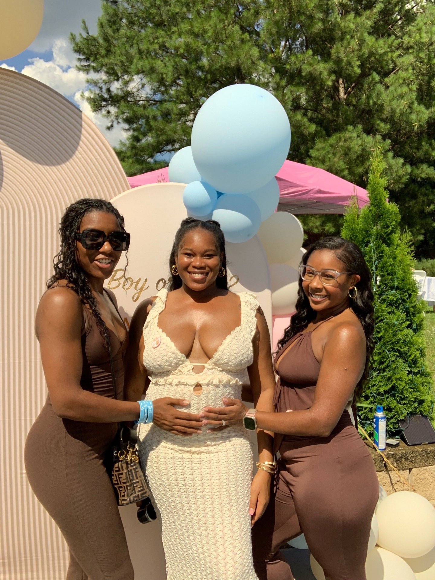 Mom-to-be and friends posing at a Boy or Girl baby shower photo booth backdrop