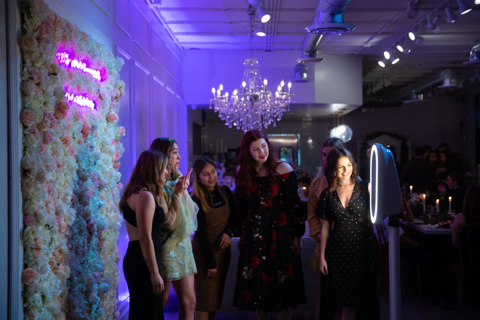 Guests posing at a PhiNik's MobiPix photo booth beside a floral wall at an Atlanta event