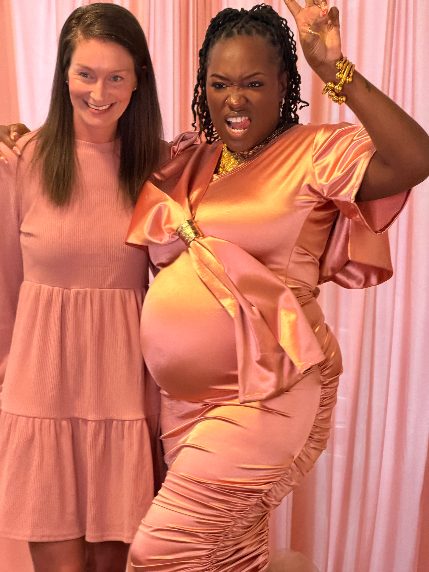 Two guests posing in front of a pink drapery photo booth backdrop
