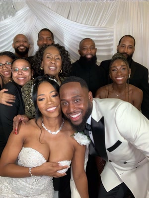 Bride and groom surrounded by family posing at a white drapery wedding photo booth backdrop