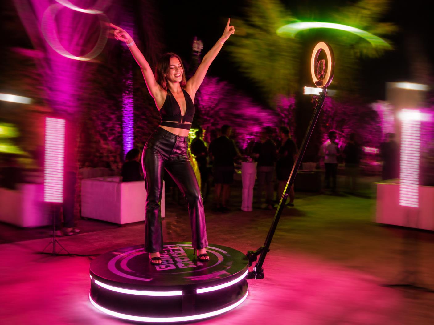 Guest on a 360 spinning video booth platform with colorful lighting